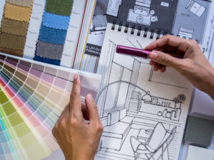 Interior decorator's hand working with illustration sketch, material and colour samples.