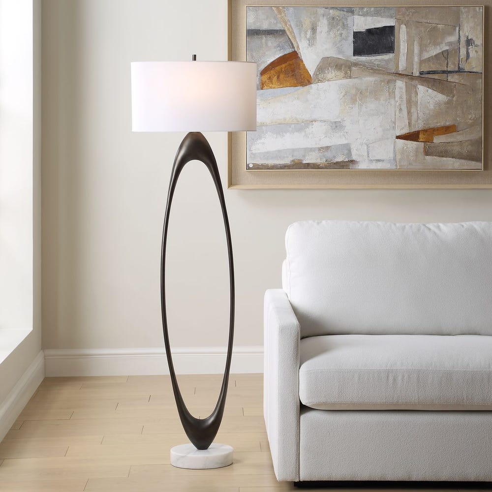 Sculptural floor lamp with marble base and curved frame – contemporary lighting trend with natural materials.